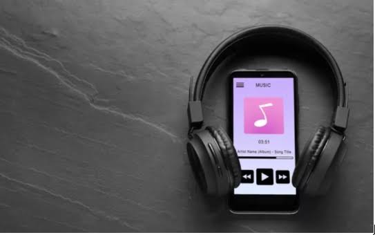 Headphones and smartphone with a music playlist on screen